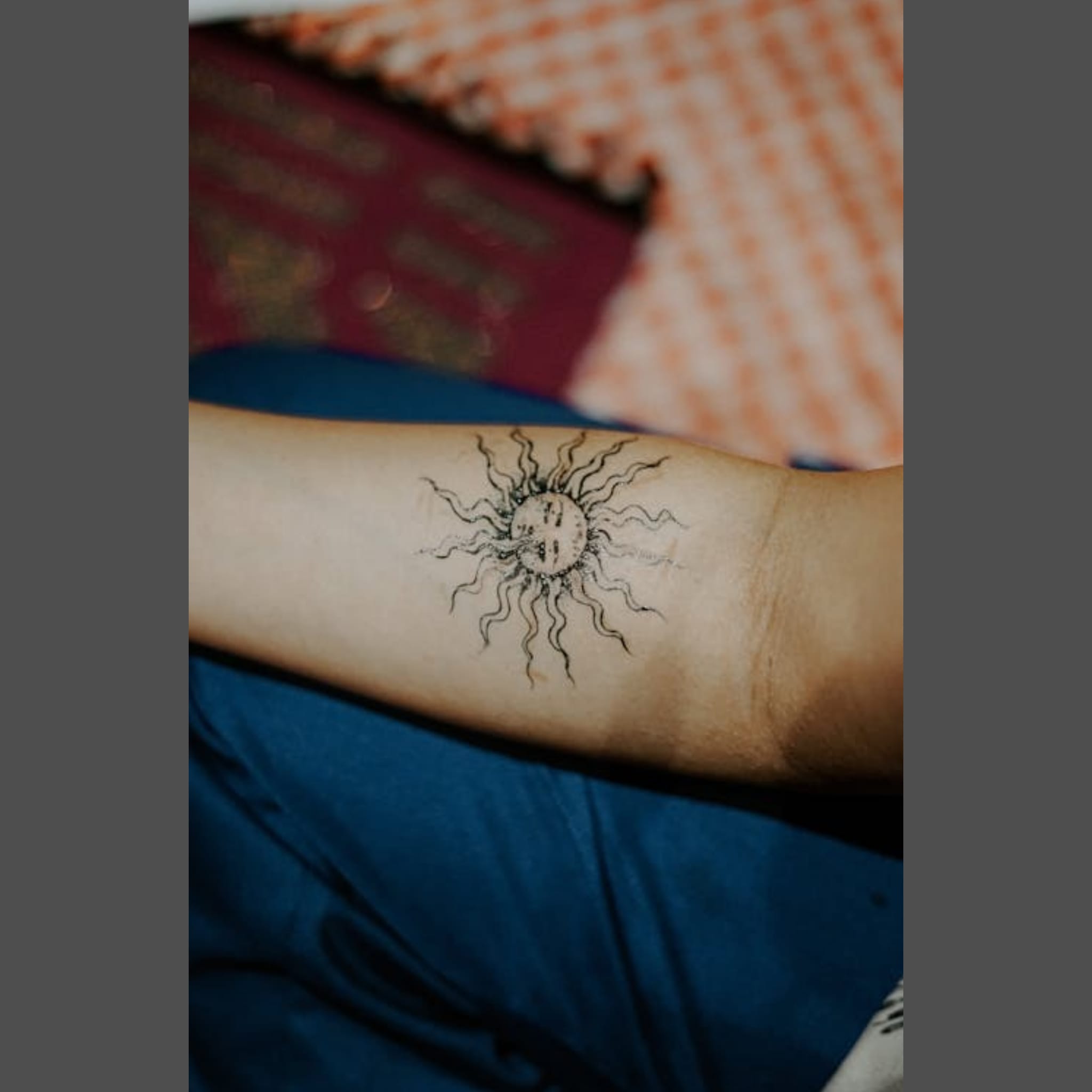 Black linework tattoo of a sun